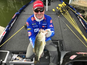 Shaw Grigsby holding a largemouth bass on the deck of his boat